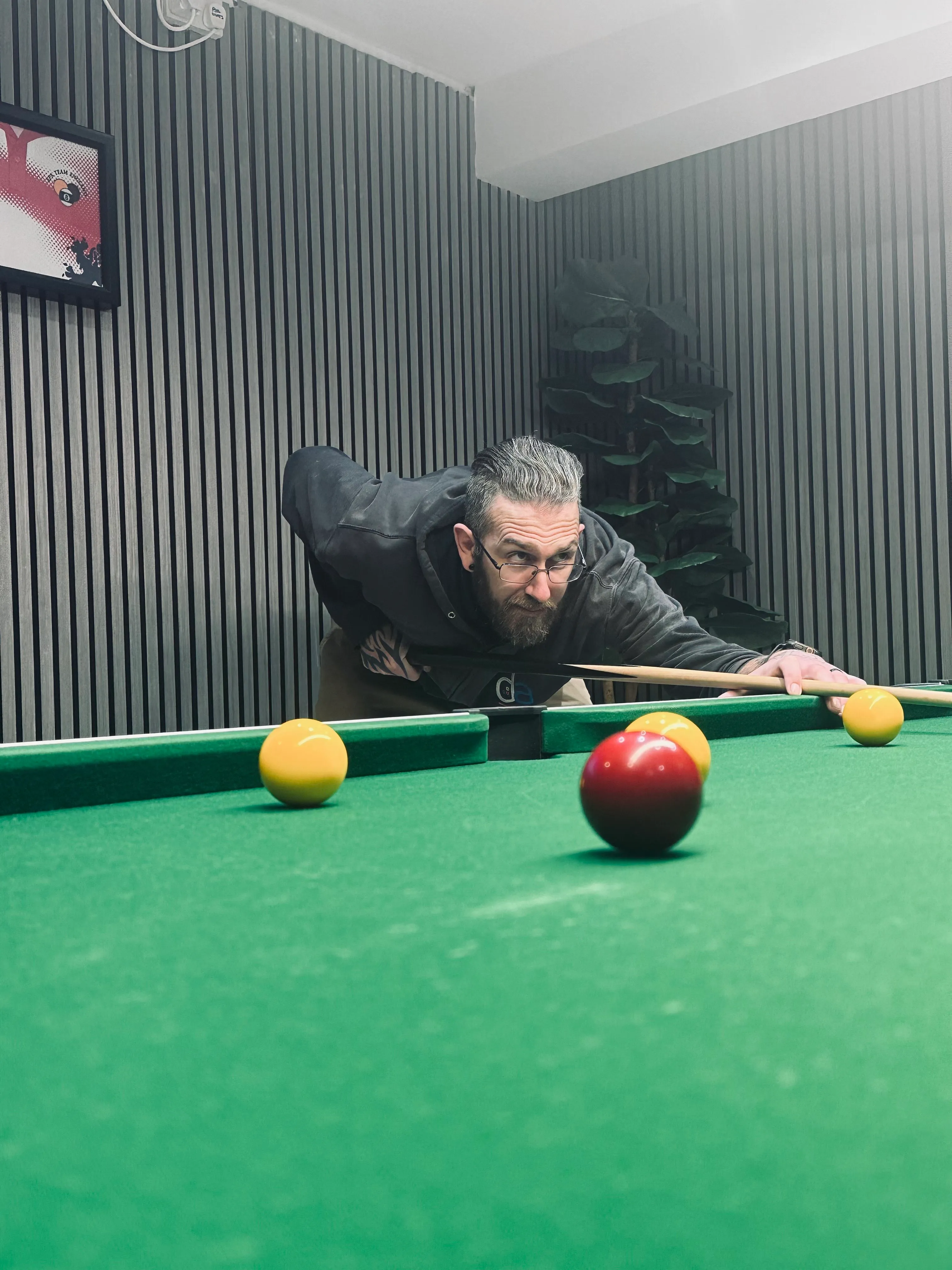 A man leaning over a pool table with two balls.